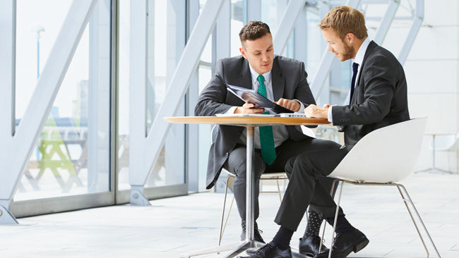 Zwei junge Männer sitzen an einem Tisch und reden über Aesculap Aeos®