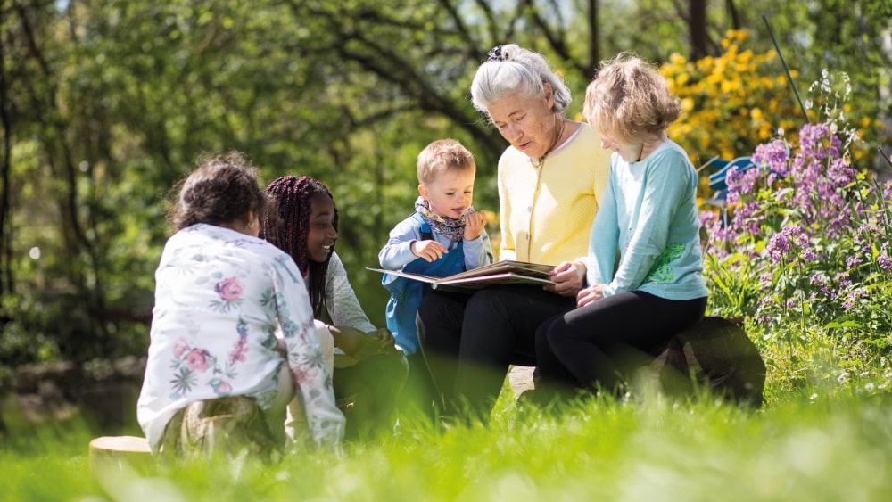 ältere Frau liest Kindern aus einem Buch vor