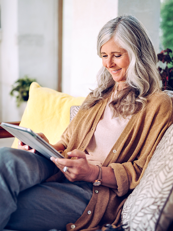 Eine Frau sitzt auf dem Sofa und liest auf ihrem Tablet